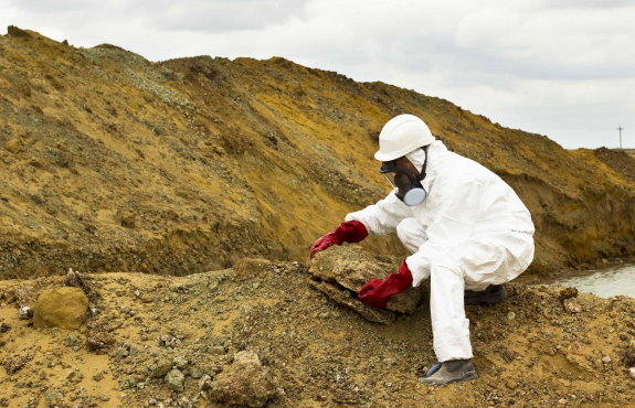 Aurora Environmental staff member sampling asbestos and soil at a contaminated site.